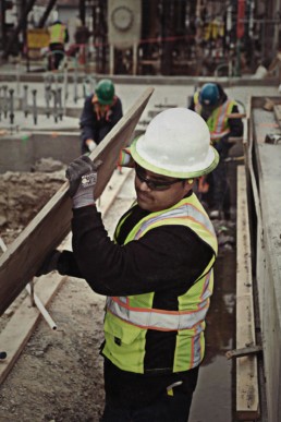 Cunstruction worker carrying wood plank for concrete form - Pipe Support Replacement